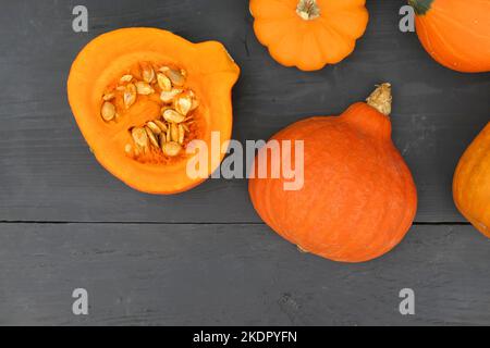 Orangefarbener Hokkaido-Kürbis mit Samen auf schwarzem Holzhintergrund schneiden. Stockfoto