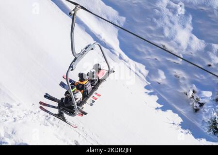 Skifahrer steigen mit dem Lift auf den Berg. Skifahren im Winter. Stockfoto