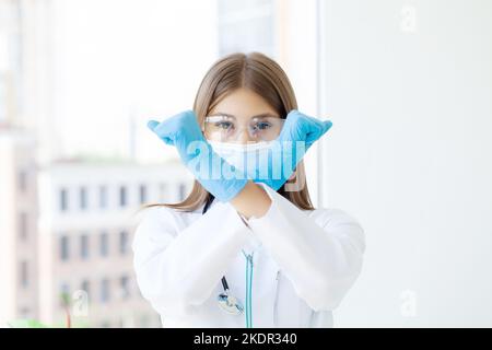 Junge europäische Ärztin, die die Arme kreuzt und negative Zeichen tut Stockfoto