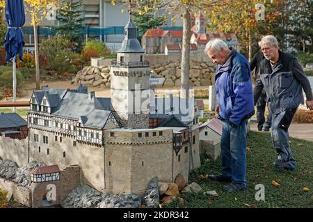Wernigerode, Deutschland. 08.. November 2022. Mitarbeiter stehen vor dem Modell der Burg Falkenstein. Im Miniaturpark endete am 06. November die Besuchersaison. Die Modelle zahlreicher Harzer Sehenswürdigkeiten werden in den kommenden Tagen gelagert. Bis zur Eröffnung der Saison im nächsten Jahr werden die durch das Wetter verursachten Schäden repariert. Im Laufe des Jahres konnten mehr als 130000 Besucher im Bürger- und Miniaturpark begrüßt werden. Quelle: Matthias Bein/dpa/Alamy Live News Stockfoto