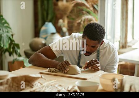 Warm getöntes Porträt eines männlichen Künstlers, der handgemachte Keramikschale im Töpferstudio formt Stockfoto