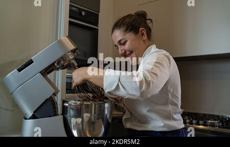 Porträt einer lächelnden Konditorin, die ihren Teig in ihrer Konditorei betrachtet Stockfoto