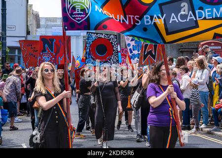 Mitarbeiter und Schüler der Mounts Bay Academy mit Spruchbändern und Plakaten Trommler bei der Mazey Day Parade beim Golowan Festival in Penzance in Cornwa Stockfoto