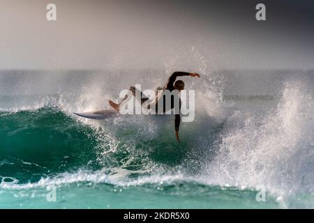 Die spektakuläre Surfaktion als männlicher Surfer wird ausgelöscht, wenn er auf einer Welle im britischen Fistral in Newquay in Cornwall reitet. Stockfoto