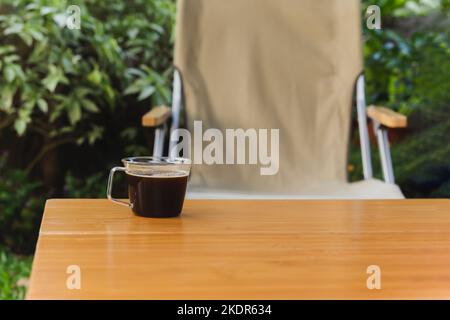 Tasse schwarzen Kaffee auf einem Holztisch im Garten. Stockfoto