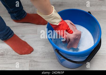 Frau wringen einen nassen Lappen in einen Eimer. Hand wringen einen nassen Lappen aus. Hochwertige Fotos Stockfoto