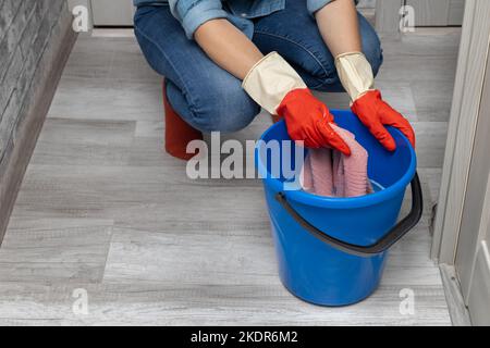 Die Hand nimmt einen nassen Lappen aus einem Eimer Wasser. Die Hand wringen einen nassen Lappen aus. Hochwertige Fotos Stockfoto