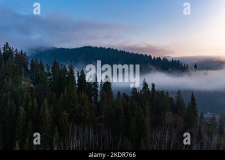 Berg atmosphärische Landschaft von hohen Bergen in dichtem Nebel bei regnerischem Wetter, Panorama von Berggipfeln in dicken Wolken, Morgendämmerung in den Bergen in EA Stockfoto