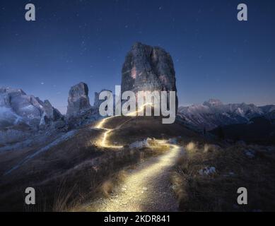 Taschenlampe Wanderwege auf Bergpfad gegen hohe Felsen in der Nacht Stockfoto