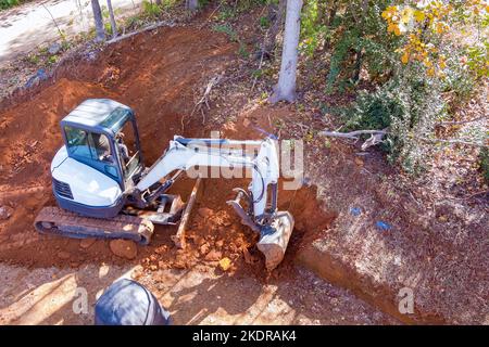 Bei Erdarbeiten auf der Baustelle mit Raupenbaggern wird der Boden für den Traktor mit Schaufelschaufeln gegraben Stockfoto