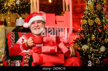 Den Moment fangen. Geschenke vom weihnachtsmann. Geschenke am Weihnachtsbaum. Frohe Weihnachten. bärtiger Mann gehen einkaufen. weihnachtsgeschenke. Winterurlaub einkaufen Stockfoto