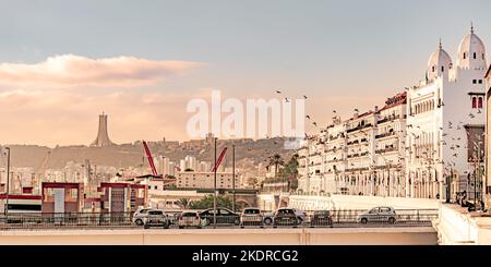 Wilaya Hauptquartier mit fliegenden Vögeln, geparkten Autos und arabischen Flaggen. Das Märtyrerdenkmal und ein blauer Himmel. Stockfoto