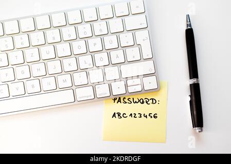 Draufsicht auf gelben Klebehinweis mit unsicherem Kennwort unter der Computertastatur auf dem Schreibtisch, Sicherheitskonzept Stockfoto