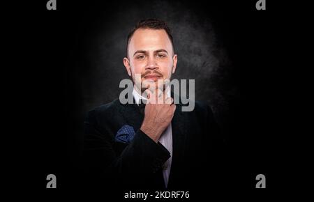 Hübscher junger modischer Mann auf dunklem Hintergrund. Stockfoto