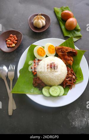 nasi Lemak, ist traditionell malaiisch gekochte Eier, Bohnen, Sardellen, Chili-Sauce, Gurke. Aus Gericht auf einem Bananenblatt serviert Stockfoto
