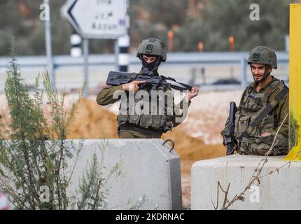 Qalqilya, Palästina. 8.. November 2022. Israelische Soldaten bewachen den blockierten Eingang zum Dorf Azzun. Die israelische Armee schloss das Tor des Dorfes Azzun, östlich der Stadt Kalqilya im Westjordanland, nachdem palästinensische Jugendliche Steine auf die Fahrzeuge jüdischer Siedler geworfen hatten. Die israelische Armee teilte mit, dass ein israelischer Siedler aus der Siedlung Kedumim infolge seiner Wunden getötet wurde, die er erlitten hatte, nachdem er von einem Palästinenser erstochen wurde. Stockfoto