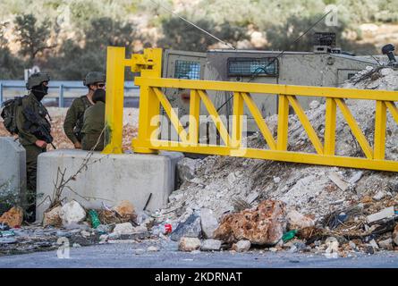 Qalqilya, Palästina. 8.. November 2022. Israelische Soldaten bewachen den blockierten Eingang zum Dorf Azzun. Die israelische Armee schloss das Tor des Dorfes Azzun, östlich der Stadt Kalqilya im Westjordanland, nachdem palästinensische Jugendliche Steine auf die Fahrzeuge jüdischer Siedler geworfen hatten. Die israelische Armee teilte mit, dass ein israelischer Siedler aus der Siedlung Kedumim infolge seiner Wunden getötet wurde, die er erlitten hatte, nachdem er von einem Palästinenser erstochen wurde. Stockfoto