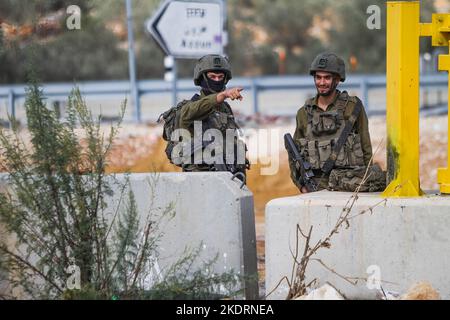 Qalqilya, Palästina. 8.. November 2022. Israelische Soldaten bewachen den blockierten Eingang zum Dorf Azzun. Die israelische Armee schloss das Tor des Dorfes Azzun, östlich der Stadt Kalqilya im Westjordanland, nachdem palästinensische Jugendliche Steine auf die Fahrzeuge jüdischer Siedler geworfen hatten. Die israelische Armee teilte mit, dass ein israelischer Siedler aus der Siedlung Kedumim infolge seiner Wunden getötet wurde, die er erlitten hatte, nachdem er von einem Palästinenser erstochen wurde. Stockfoto