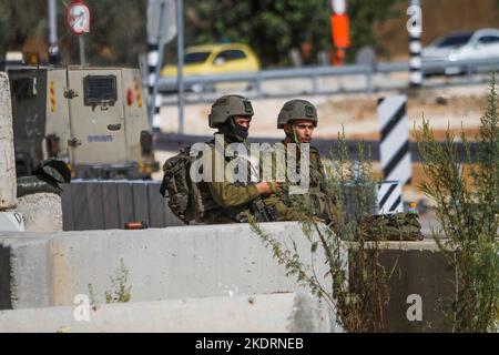 Qalqilya, Palästina. 8.. November 2022. Israelische Soldaten bewachen den blockierten Eingang zum Dorf Azzun. Die israelische Armee schloss das Tor des Dorfes Azzun, östlich der Stadt Kalqilya im Westjordanland, nachdem palästinensische Jugendliche Steine auf die Fahrzeuge jüdischer Siedler geworfen hatten. Die israelische Armee teilte mit, dass ein israelischer Siedler aus der Siedlung Kedumim infolge seiner Wunden getötet wurde, die er erlitten hatte, nachdem er von einem Palästinenser erstochen wurde. Stockfoto