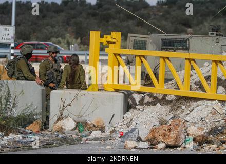 Qalqilya, Palästina. 8.. November 2022. Israelische Soldaten bewachen den blockierten Eingang zum Dorf Azzun. Die israelische Armee schloss das Tor des Dorfes Azzun, östlich der Stadt Kalqilya im Westjordanland, nachdem palästinensische Jugendliche Steine auf die Fahrzeuge jüdischer Siedler geworfen hatten. Die israelische Armee teilte mit, dass ein israelischer Siedler aus der Siedlung Kedumim infolge seiner Wunden getötet wurde, die er erlitten hatte, nachdem er von einem Palästinenser erstochen wurde. Stockfoto