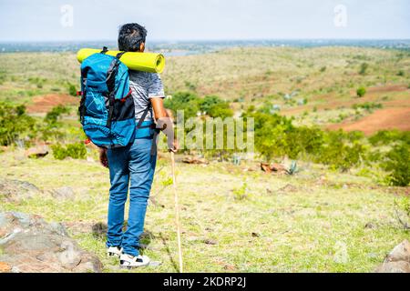 Rückansicht Aufnahme eines Wanderers mittleren Alters, der von der Bergspitze herunterkommt - Konzept von Wohlbefinden, Hobby und Freiheit. Stockfoto