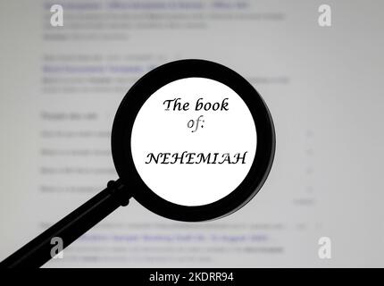 Das Buch Nehemiah aus der Heiligen Bibel, das in einer Vergrößerungsklasse dargestellt ist, wurde vergrößert. Stockfoto