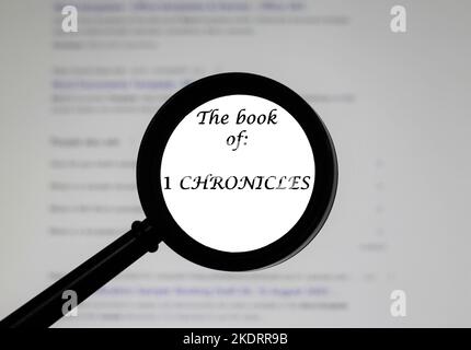 Das Buch der Chroniken von 1 aus der Heiligen Bibel, das in einer Vergrößerungsklasse abgebildet ist, wurde vergrößert. Stockfoto