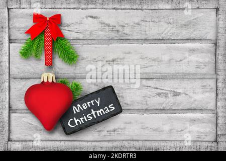 Fröhliches Weihnachtsetikett und Dekoration mit rotem Herz und Tannenzweigen auf Holzhintergrund Stockfoto