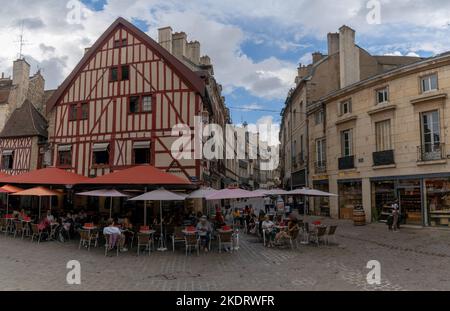 Dijon, Frankreich - 14. September 2022: Malerisches französisches Café im Freien in der historischen Altstadt von Dijon mit Fachwerkhäusern dahinter Stockfoto