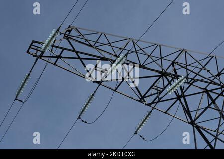 Als Teil eines Hochspannungsmasten werden Kabel für den Transport großer Mengen elektrischer Energie über relativ große Entfernungen befestigt Stockfoto