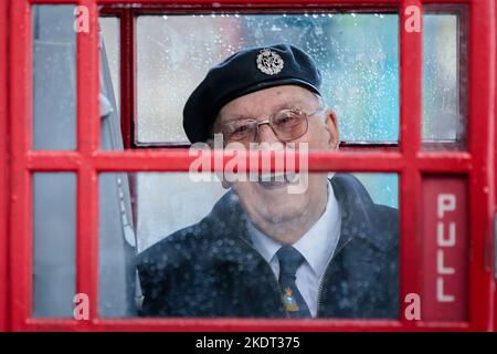 Wetter in Großbritannien, London, Großbritannien. 8.. November 2022. Ein britischer Militärveteran nimmt während einer schweren Dusche in Whitehall in einer roten Telefonbox in der Nähe des Cenotaph Schutz. Foto von Amanda Rose/Alamy Live News Stockfoto