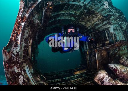 Scuba Diwer schwimmt auf einem geschlossenen Kreislauf durch das Wrack eines alten Flugzeugs unter Wasser Stockfoto