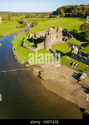 Luftaufnahme von Trittsteinen über einen kleinen Fluss, der zu den Ruinen einer alten Burg führt (Ogmore Castle, Glamorgan, Wales) Stockfoto