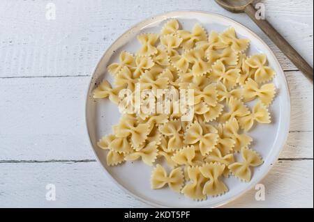 Gekochte Farfalle oder Fliege Pasta auf einem Teller auf weißem Hintergrund Stockfoto