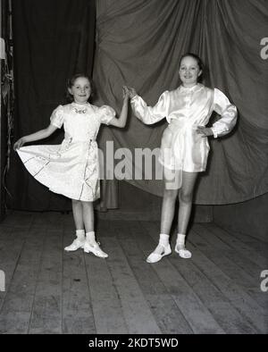 1955, historisch, zwei junge Mädchen, die in der Winterpantomine auftreten, Robin Hood, in ihren Kostümen, posieren zusammen auf der Bühne für ein Foto, Leeds, England, Großbritannien. Stockfoto