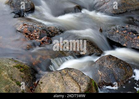 Wasser fließt in Zeitlupe in Stromschnellen über Felsen Stockfoto