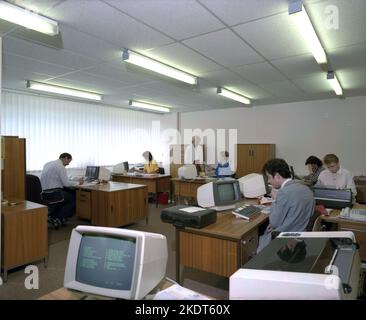 1980s, historisch, Blick über ein offenes Büro der Ära, männliche und weibliche Mitarbeiter, die an Schreibtischen arbeiten, mit kleinen Desktop-Computer-Terminals, höchstwahrscheinlich von IBM, England, Großbritannien. Als CRT-Monitore zeigten sie den Text grün an, wie im Bild zu sehen, und wurden so als „Green Screen Terminals“ bekannt. Stockfoto