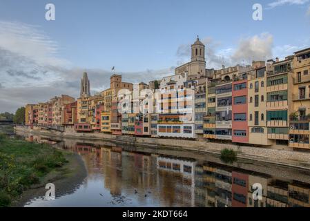 Ein Blick auf farbenfrohe Gebäude, die Kirche des heiligen Felix und die Kathedrale der heiligen Maria von Girona spiegeln sich im Fluss Onya wider Stockfoto