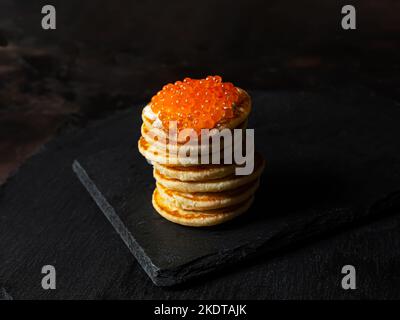 Roter Kaviar auf einem Stapel Pfannkuchen mit saurer Creme auf einem Schiefer Stockfoto