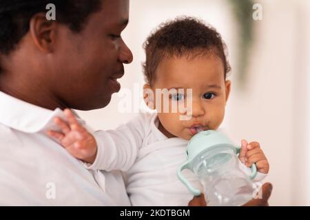 Schwarzer Junge Trinkt Wasser Aus Der Flasche, Während Er Zeit Mit Dem Vater Verbringt Stockfoto