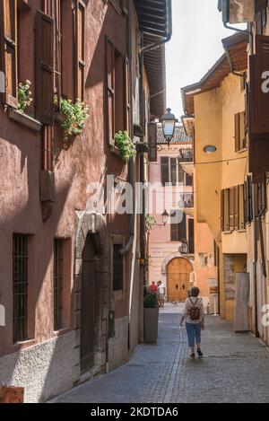 Reife Frauen reisen, Rückansicht im Sommer einer Frau mittleren Alters, die einen Rucksack trägt und alleine eine malerische Straße in einer italienischen Stadt, Italien, Europa, erkundet Stockfoto