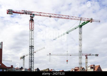 Mehrere hohe Turmdrehkrane auf städtischen Baustellen vor bewölktem Himmel Stockfoto