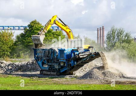 Fahrbare Beton- und Stahlbetonbauschutt-Zerkleinerungsmaschine in Aktion, Bauschutt-Recycling in feinere Fraktionen Stockfoto