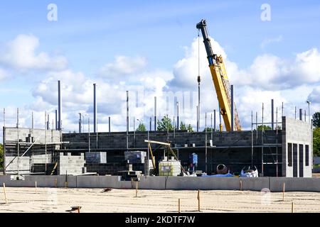 Baustelle für ein neues Industriegebäude, geschäumte Betonblockwände, Stahlbetonstützen und einen Teleskopkran Stockfoto