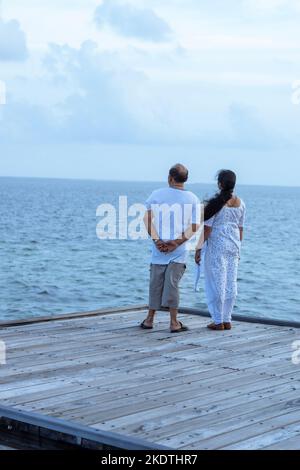 Ein Bild von zwei Paaren, die am Rand einer Plattform stehen und das wunderschöne blaue Meer und den Himmel betrachten Stockfoto