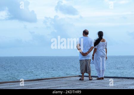 Ein Bild von zwei Paaren, die am Rand einer Plattform stehen und das wunderschöne blaue Meer und den Himmel betrachten Stockfoto