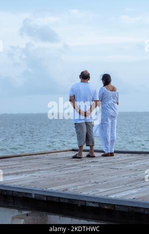 Ein Bild von zwei Paaren, die am Rand einer Plattform stehen und das wunderschöne blaue Meer und den Himmel betrachten Stockfoto