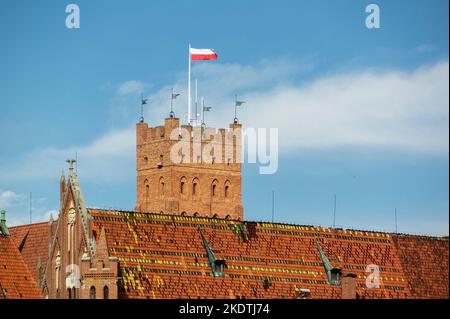 Polnische Flagge winkt auf einem Fahnenmast am Turm des Schlosses Malbork in Polen Stockfoto