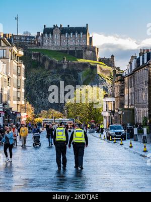 Zwei Polizisten patrouillieren in der Castle Street mit dem Aufschluss des Edinburgh Castle, Schottland, Großbritannien Stockfoto