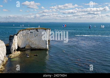 Old Harry's Rocks mit Leuten auf Jet Skis und Paddle Boards in der Nähe und einer Segelregatta im Hintergrund, Studland, Dorset, Großbritannien, Juli. Stockfoto